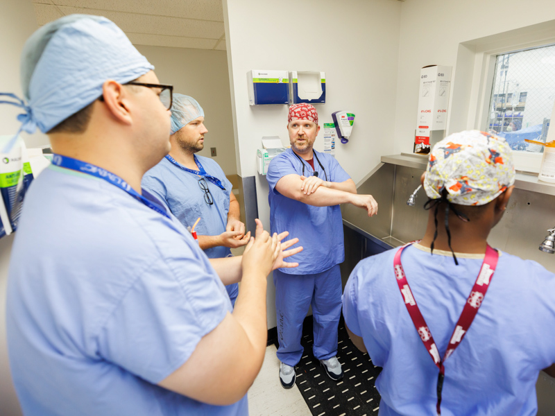 Surgical tech James Burnett shows new surgical residents how to scrub in. From left are Dr. Humberto Aparicio, Dr. Aaron Hurd and Dr. Akeelein Forrest. Melanie Thortis/ UMMC Communications